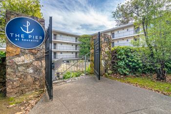 A gate with a blue sign in front of an apartment building